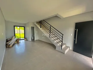 Ambiente interno com escadaria e porta de vidro abrindo para o exterior.