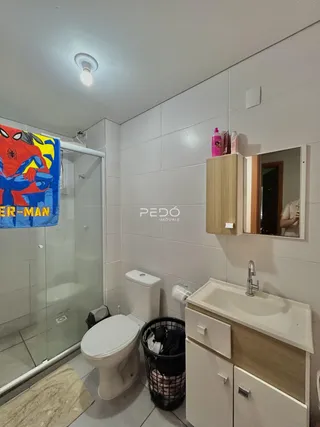Foto de um banheiro com revestimento cerâmico e box de vidro.
