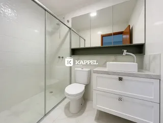 Banheiro com box de vidro e bancada branca.