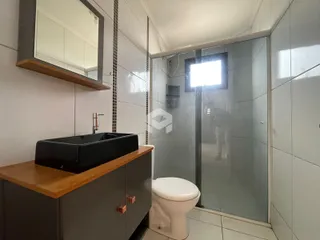 Banheiro com box de vidro e revestimento branco.
