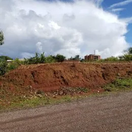 Vista externa mostrando um monte de terra avermelhada ao lado de uma estrada.