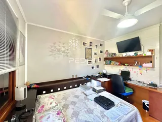 Quarto com cama e área de trabalho em um imóvel no Brasil.