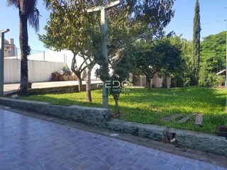Vista externa do terreno com gramado e vegetação ao lado de uma calçada.