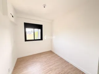 Ambiente interno de uma sala com piso de madeira clara e paredes brancas.