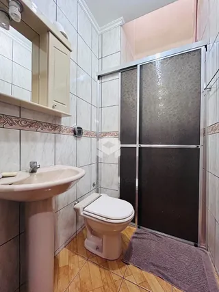 Foto de um banheiro com azulejos brancos e louças sanitárias.