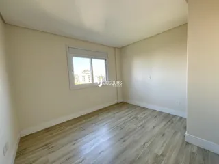 Ambiente interno de uma sala com piso de madeira clara e janela.