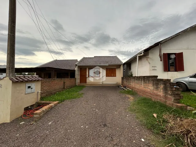 Vista externa de uma residência com muro de tijolos e entrada de cascalho.