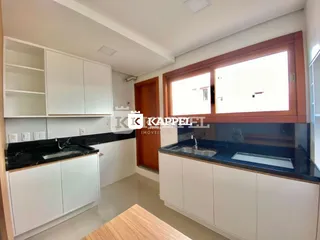 Esta é uma foto de uma cozinha com armários brancos e bancadas escuras.