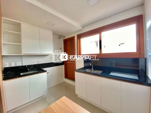 Esta é uma foto de uma cozinha com armários brancos e bancadas escuras.