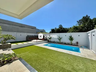 Vista aérea de uma piscina e jardim com gramado verde em uma propriedade.