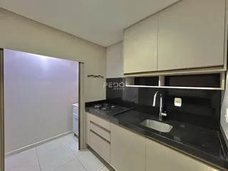 Cozinha com armários superiores e bancada escura.