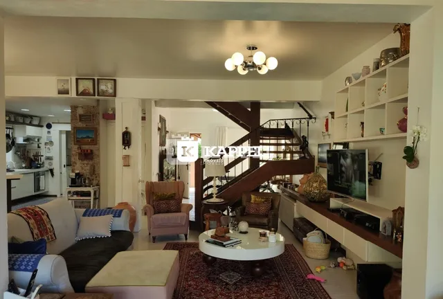 Sala de estar ampla com sofá e escadaria de madeira em uma residência.