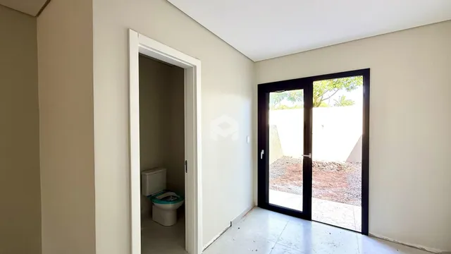 Vista de um corredor interno com porta de entrada e porta de vidro que dá para o exterior.