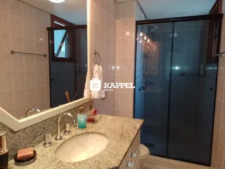 Banheiro com bancada de granito e box de vidro transparente.