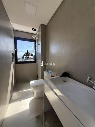 Foto de um banheiro moderno com janela e vaso sanitário.
