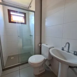Foto de um banheiro com vaso sanitário e pia brancos.