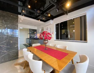Vista de uma sala de jantar com mesa de madeira e cadeiras brancas em um imóvel no Brasil.