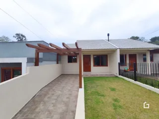 Fachada de uma residência com área externa coberta e gramado.