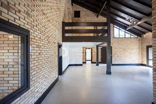Hall de entrada com paredes de tijolo aparente e piso claro.