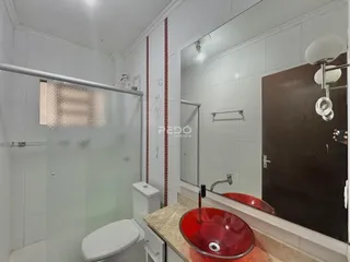 Foto de um banheiro com azulejos brancos e detalhes em vermelho.