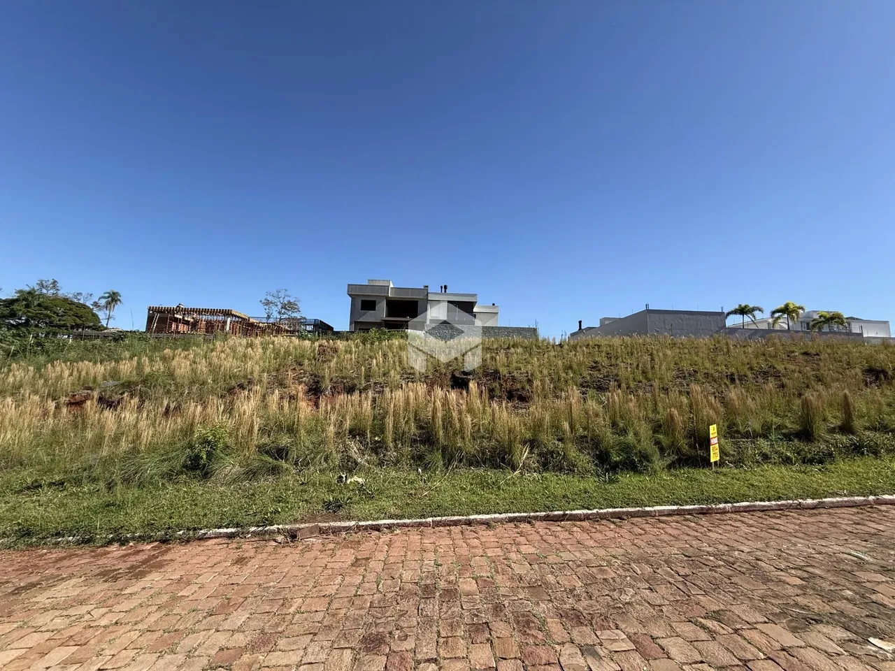 Vista da propriedade com terreno gramado e construção ao fundo.