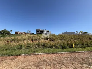 Vista da propriedade com terreno gramado e construção ao fundo.