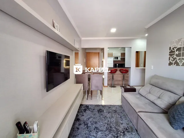 Sala de estar moderna com sofá e televisão em um ambiente claro.