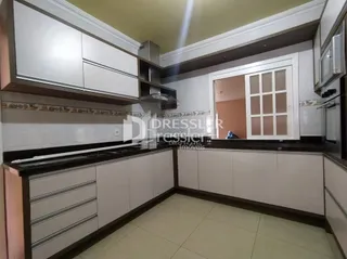 Uma cozinha com armários brancos e bancadas escuras.