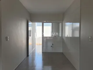 Corredor interno de uma residência com paredes brancas e piso claro.