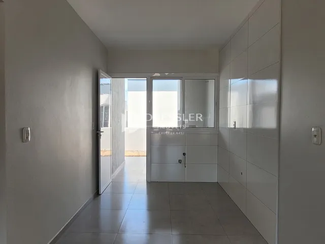 Corredor interno de uma residência com paredes brancas e piso claro.