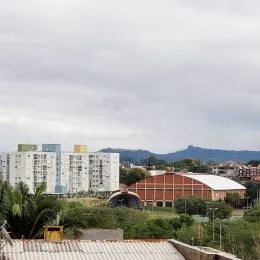 Vista externa de um prédio com telhado vermelho em uma área verde.