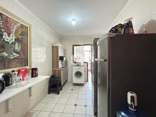 Interior de uma cozinha com revestimento de cerâmica e armários.