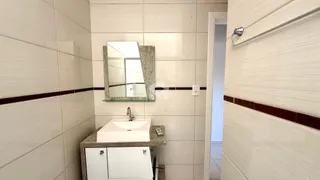 Foto de um banheiro com revestimento de azulejos brancos.