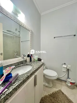 Banheiro com pia, espelho e vaso sanitário em um ambiente claro.
