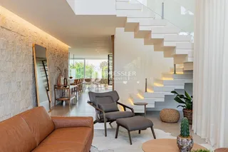 Sala de estar moderna com escadaria e vista para o exterior.