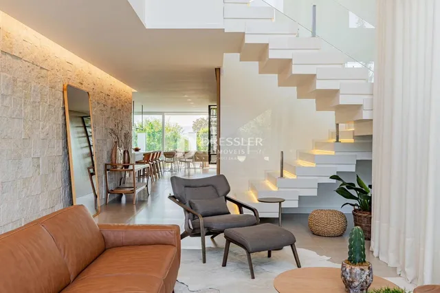 Sala de estar moderna com escadaria e vista para o exterior.