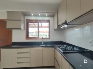 Foto de uma cozinha interna com armários claros e bancadas escuras.
