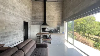 Sala de estar com paredes de tijolo e grande janela com vista para a vegetação.