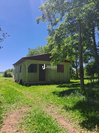 Uma casa de madeira está localizada em um campo gramado.