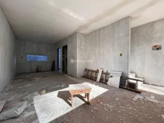 Interior de um cômodo em estado inacabado com paredes de concreto aparente.
