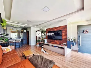 Sala de estar com sofá e televisão em um ambiente claro com piso de madeira.