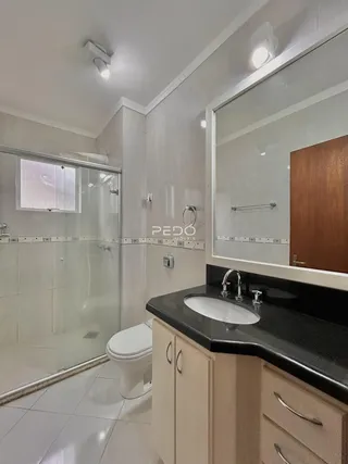 Banheiro com box de vidro e bancada moderna.