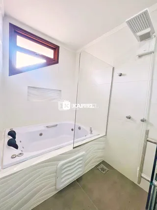 Banheiro com banheira e box de vidro em um imóvel.