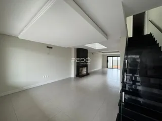 Ambiente interno de uma sala ampla com piso de cerâmica e lareira.