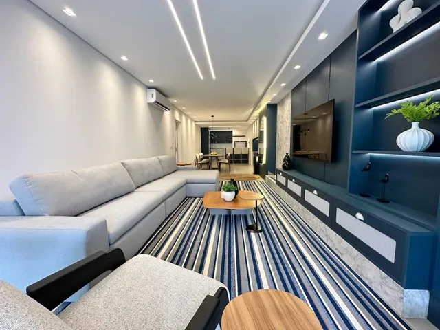 Sala de estar moderna com sofá e painéis de destaque azul escuro.