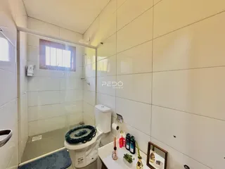 Interior de um banheiro com revestimento cerâmico e box de vidro.