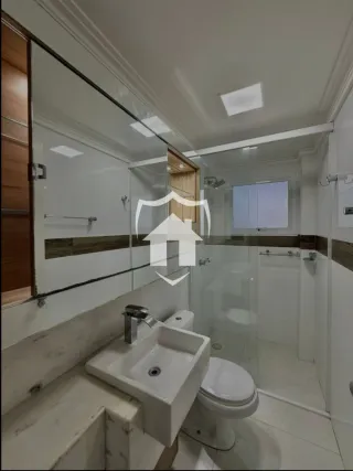 Foto interna de um banheiro com box de vidro e louças brancas.