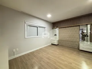 Ambiente interno de uma sala com piso de madeira clara e janela.