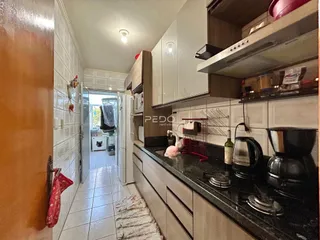 Vista de uma cozinha com piso de cerâmica e armários brancos.