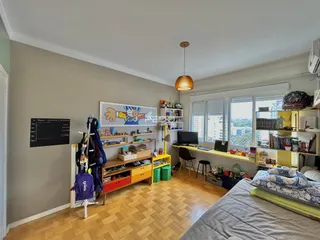 Ambiente interno de uma sala de estar com piso de madeira e janela.